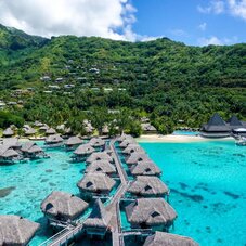 Sofitel Kia Ora Moorea Beach Resort aerial view showcasing the luxury resort, pristine white-sand beach, turquoise lagoon waters, and Moorea’s lush tropical surroundings.